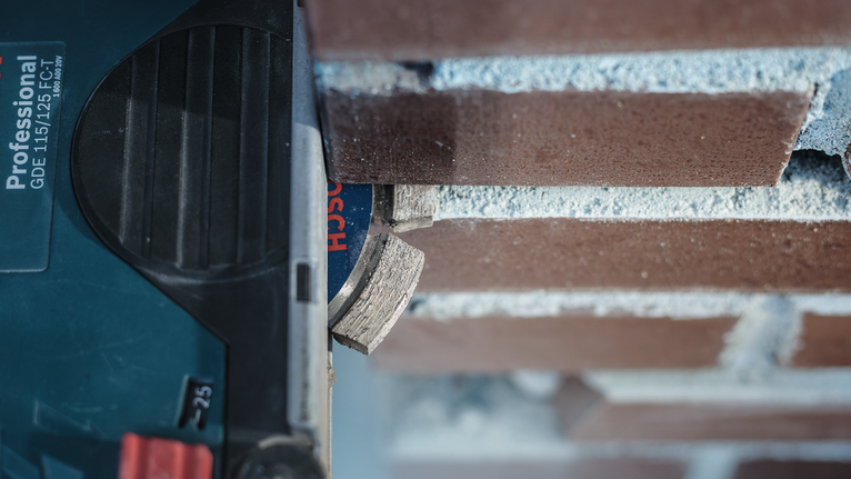 Kotoučová pila řezající drážku do cihlové zdi.