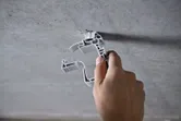 Osoba připevňuje plastovou sponu k betonovému stropu.
