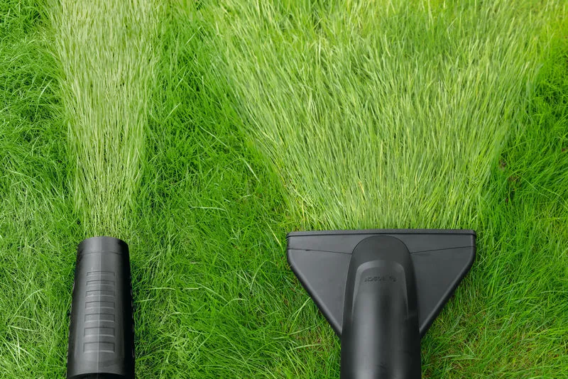 Foukač listí a vysavač na trávu vytvářejí čisté cesty skrz zelenou trávu.