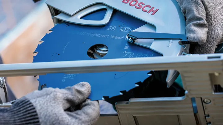 Osoba s bezpečnostním vybavením instaluje kotouč okružní pily do elektrického nářadí.