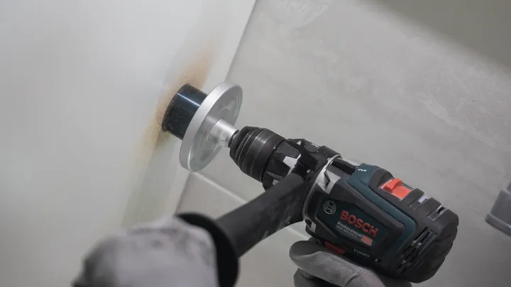 Osoba v bezpečnostním vybavení vyvrtá díru do zdi pomocí děrové pily.