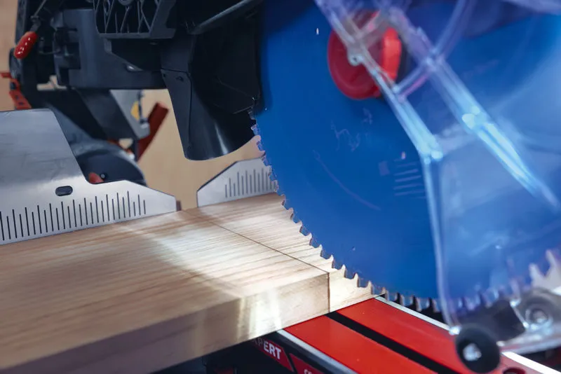 Pokosový pilový list řeže dřevěnou desku pod vyznačeným úhlem.