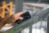 Osoba používá digitální sklonoměr k měření úhlu kovového nosníku.