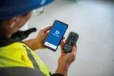 Osoba s bezpečnostním vybavením používá laserový měřič a aplikaci pro chytré telefony.