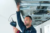 Eine Person benutzt ein Thermodetektor, um Rohre in einer Decke zu inspizieren.