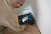 Eine Person mit Schutzausrüstung befestigt mit einem Akku-Holznagler Dielenböden.