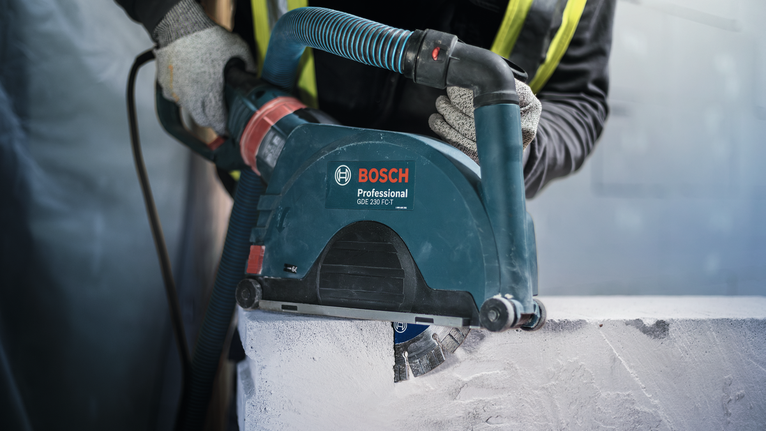 Eine Person mit Sicherheitsausrüstung schneidet Beton mit einem Elektrowerkzeug.