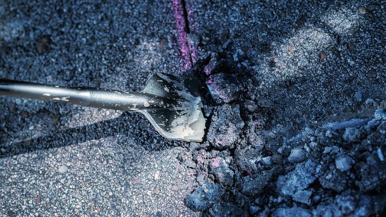 Meißel durchbricht Asphaltbelag.