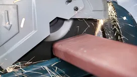 Eine Metallsäge schneidet durch einen Stahlträger und erzeugt helle Funken.