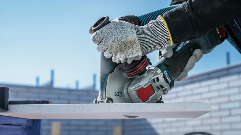 Eine Person mit Sicherheitsausrüstung schneidet mit einem Elektrowerkzeug eine weiße Tafel.