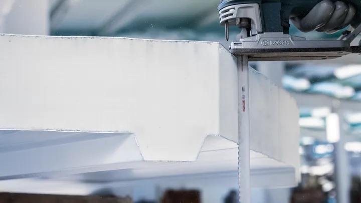 Eine Person schneidet dicke Schaumstoffplatten mit einer vertikalen Säbelsäge.