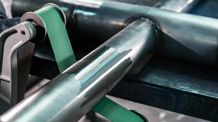 Ein Schleifwerkzeug glättet die Oberfläche eines Metallrohrs auf einer Werkbank.