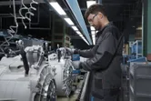 Eine Person mit Sicherheitsausrüstung montiert Maschinenteile mit einem Akku-Elektrowerkzeug.