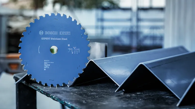 Kreissägeblatt auf einem Tisch neben abgewinkelten Metallträgern platziert.