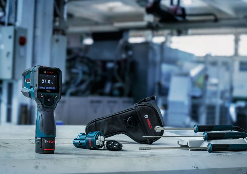 Thermometer und Sonden mit Tragekoffer auf einer Werkbank in einer industriellen Umgebung.