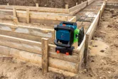Laser-Nivelliergerät mit Halterung und Befestigungselement an einer Holzschalung auf einer Baustelle.