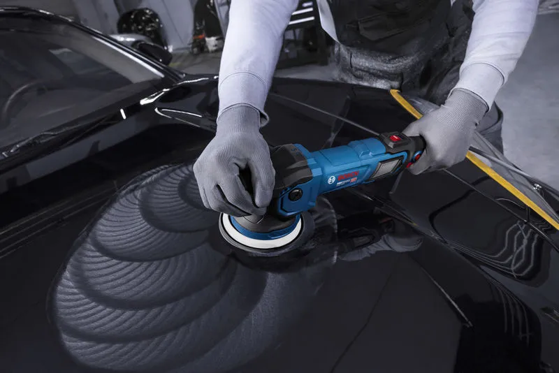 Eine Person in Schutzausrüstung poliert eine Motorhaube mit einer blauen Poliermaschine.