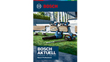 Ein Bosch Professional Rasenmäher steht auf grünem Gras, umgeben von einem Gartenbereich.