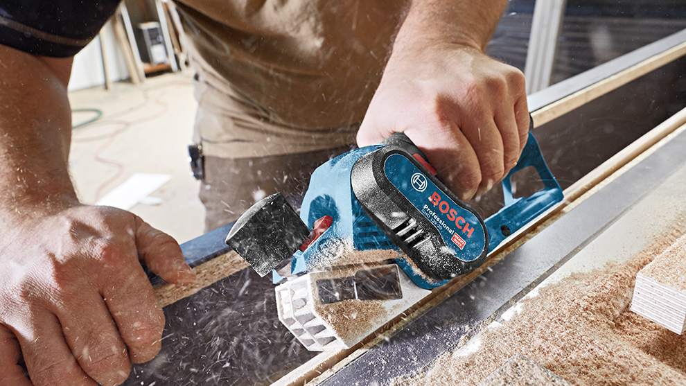 Ein Bosch Professional Elektrowerkzeug schneidet Holz, umgeben von Holzspänen.