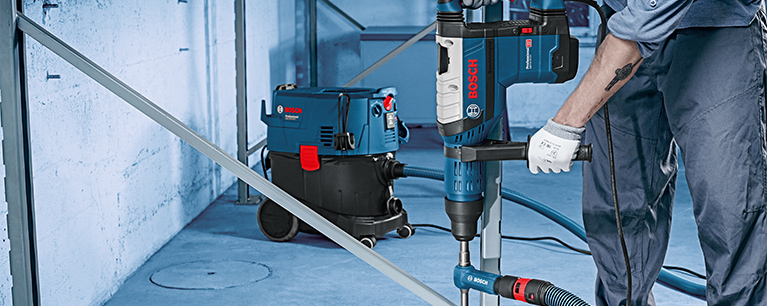 Ein Bosch Professional Bohrhammer wird von einer Person in Arbeitskleidung genutzt.