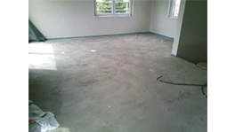 Ein leerer Raum mit grauem Boden und weißen Wänden, Fenster steht offen.