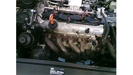 Ein Motorblock mit metallischen Komponenten und einem orangefarbenen Ölmessstab.
