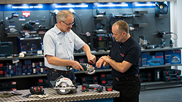 Zwei Männer prüfen Bosch Professional Werkzeuge an einem Tisch in einem Geschäft.