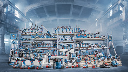 Verschiedene Bosch Professional Werkzeuge in blauer Farbe auf Regalen in einer Industriehalle.