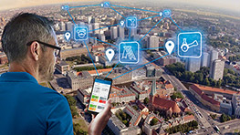 Mann mit Brille betrachtet Smartphone über einer Stadtansicht mit Icons.