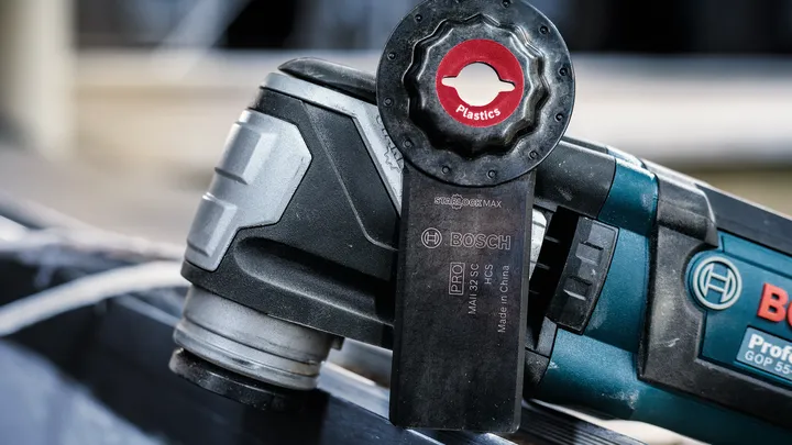 Oscillerende multiværktøj med et bladtilbehør, der bruges til at skære plastmateriale.