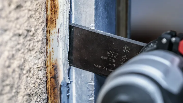 Oscillerende værktøjsklinge fjerner rust fra en metalramme.