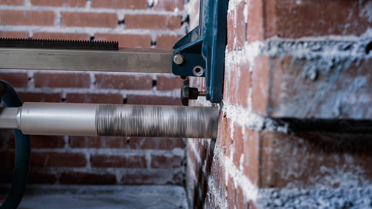 Kerneboremaskine laver et hul i en murstensvæg.