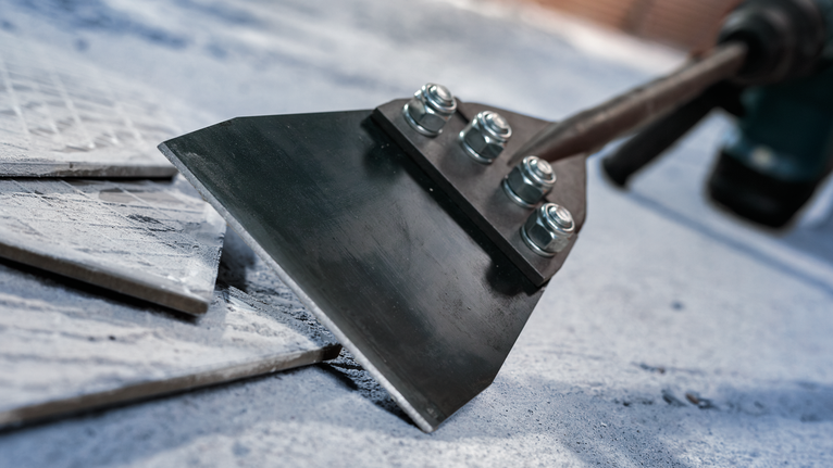 Bredt mejselblad fjerner gulvfliser fra betonoverfladen.