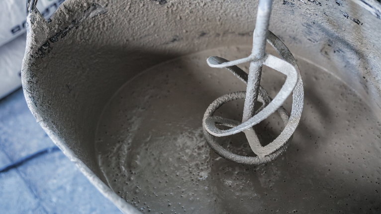 Blander, der omrører våd cement i en spand.