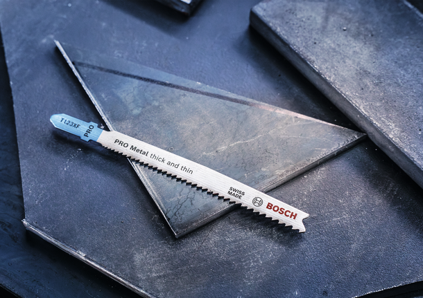 Metalstiksavklinge hviler på mørke metalplader.