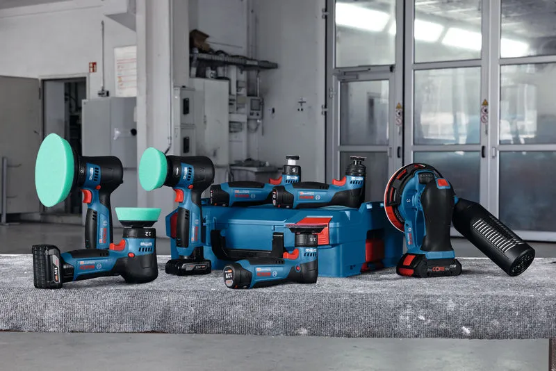 Batteridrevne polerings- og slibeværktøjer med blå opbevaringskuffert på en arbejdsbænk i et værksted.