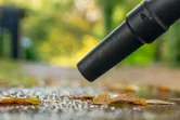 Batteridrevet løvblæser fjerner våde blade fra en sti efter regn.