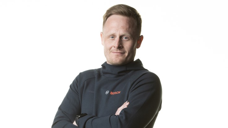 En mand i sort trøje med Bosch-logo står med korslagte arme.