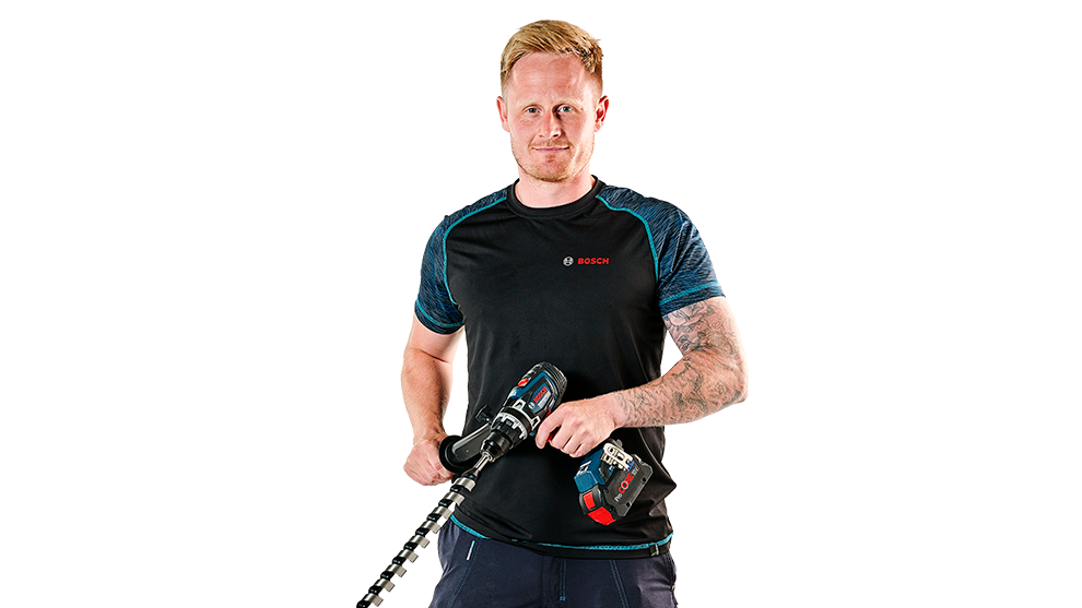 En mand holder to Bosch Professional værktøjer, iført sort t-shirt med blå detaljer.