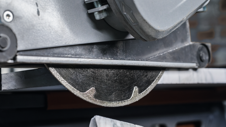 Diamond saw blade cutting a slab of stone on a workbench.