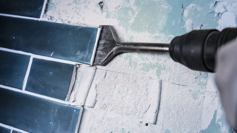 Power tool with chisel attachment removes wall tiles.