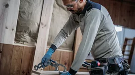 Person wearing safety equipment clamps wooden boards on a workbench.