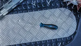 Flathead screwdriver resting on a textured metal plate.