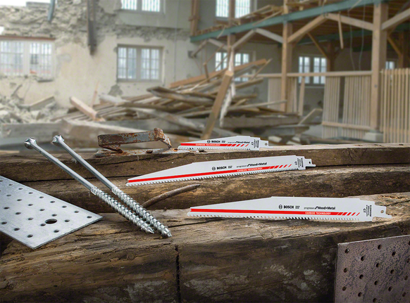 Lames de scie, vis et plaques de métal exposées sur des poutres en bois sur un chantier de construction.