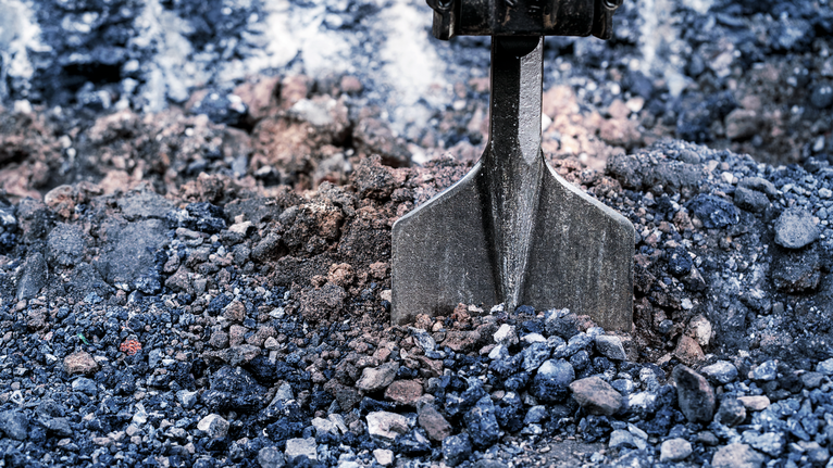 Un burin brise du gravier compacté sur un chantier de construction.