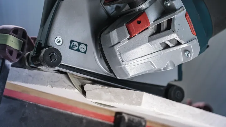 Outil électrique coupant un carreau de céramique sur un établi.