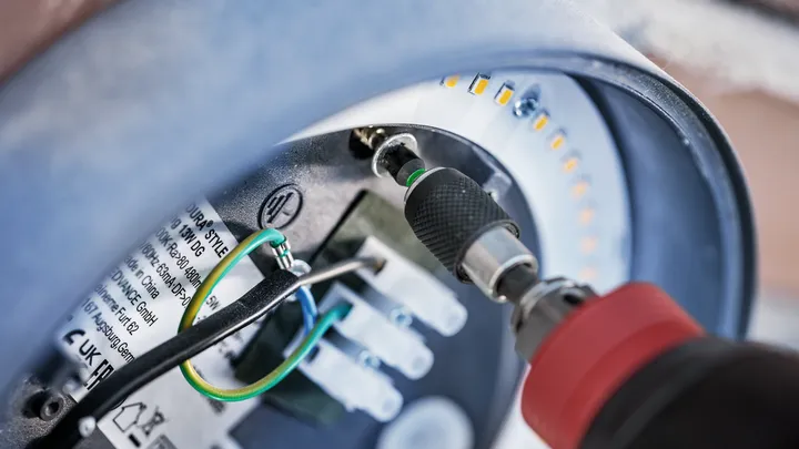 Tournevis sans fil serrant une vis à l'intérieur d'un luminaire LED circulaire.