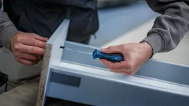 Une personne utilisant un tournevis pour fixer une vis dans un cadre métallique.