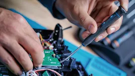 Une personne utilisant un tournevis pour travailler sur des composants électroniques.