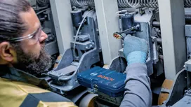 Une personne portant un équipement de sécurité utilise une clé à cliquet sur une machine industrielle.